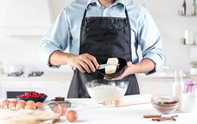 Homem a cortar um pedaço de manteiga para utilizar para cozinhar