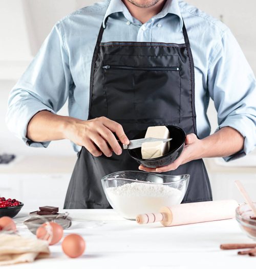 Homem a cortar um pedaço de manteiga para utilizar para cozinhar