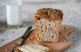 Tábua de corte com pão e fatia de pão com manteiga