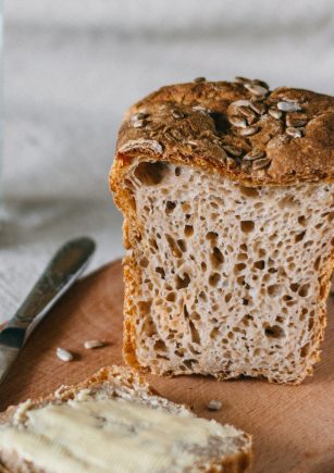 Tábua de corte com pão e fatia de pão com manteiga