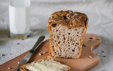 Tábua de corte com pão e fatia de pão com manteiga