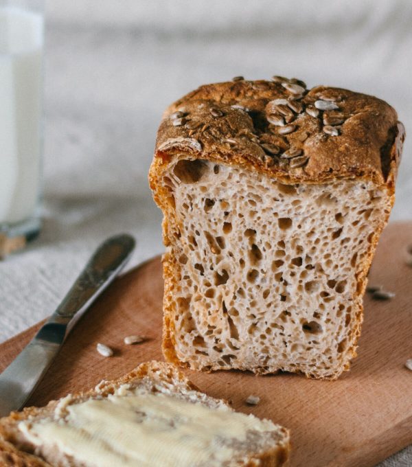 Tábua de corte com pão e fatia de pão com manteiga